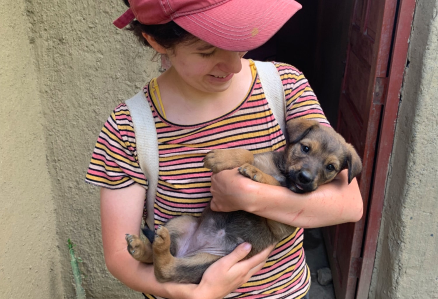 Puppy love! a female intern dressed in a stripey top and red cap cradles a young puppy in her arms