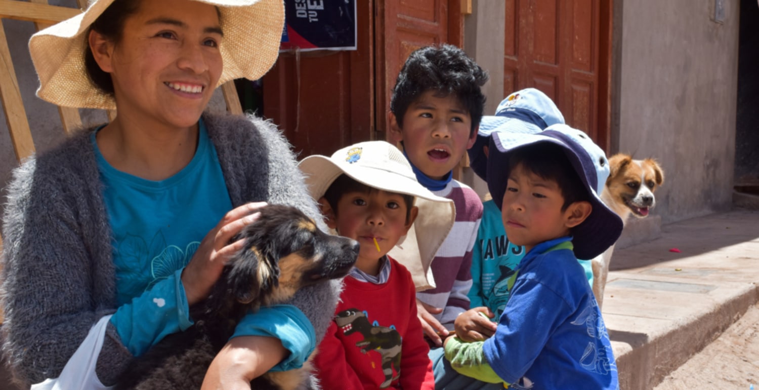 Lourdes, a responsible owner who cares about animal welfare Lady wearing a hat holding a puppy in her arms with her three young sons in the background