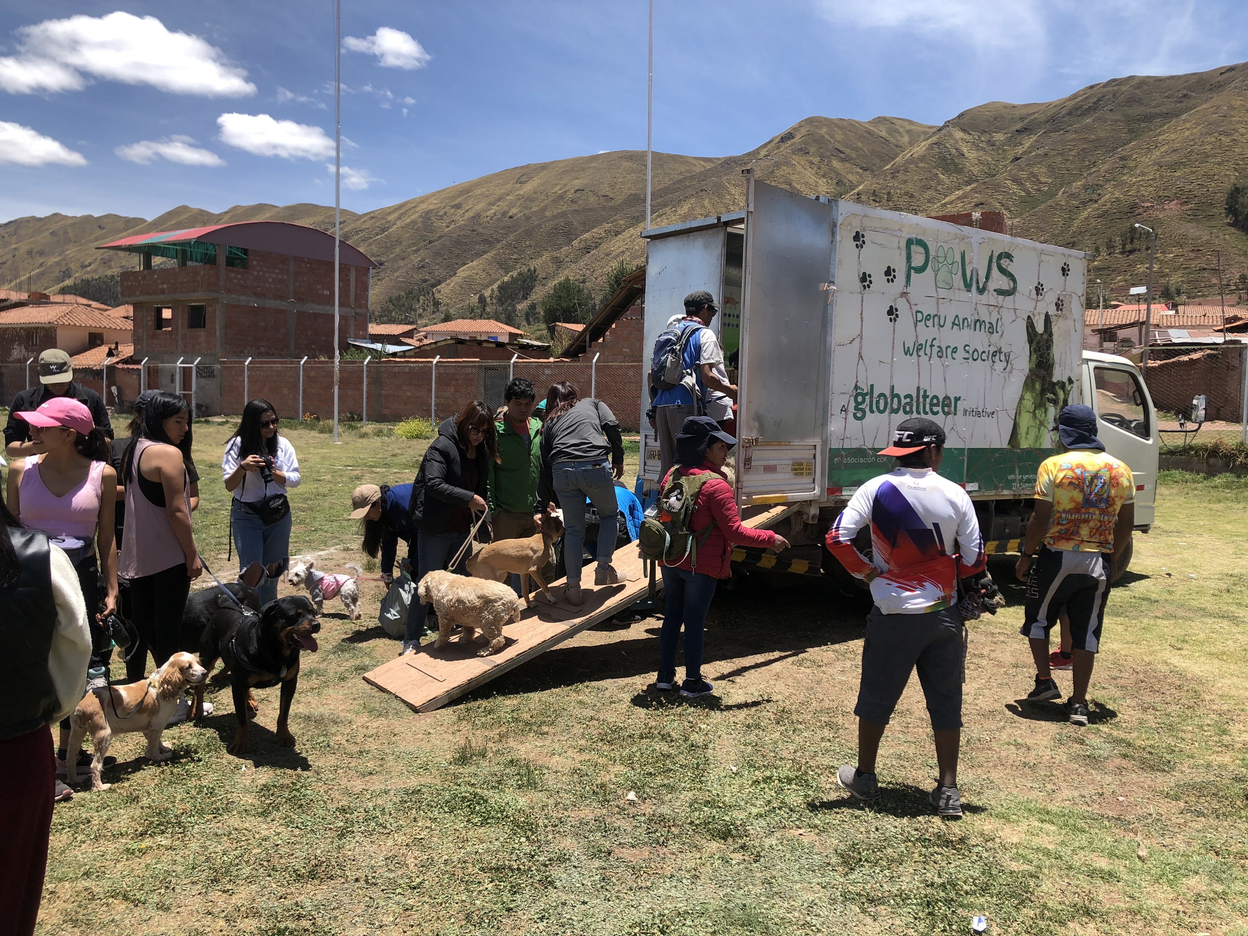 Dogs and owners waiting to receive treatment from PAWS Dog owners and dogs waiting outside PAWS truck"