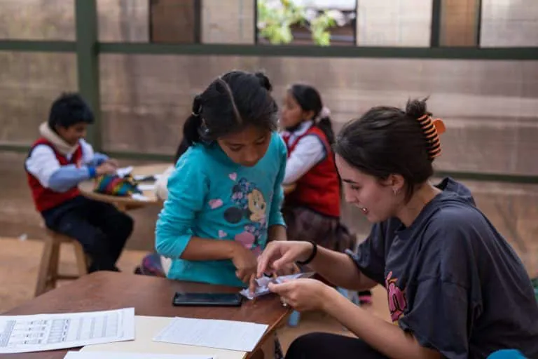 Volunteer working with children at a classroom table