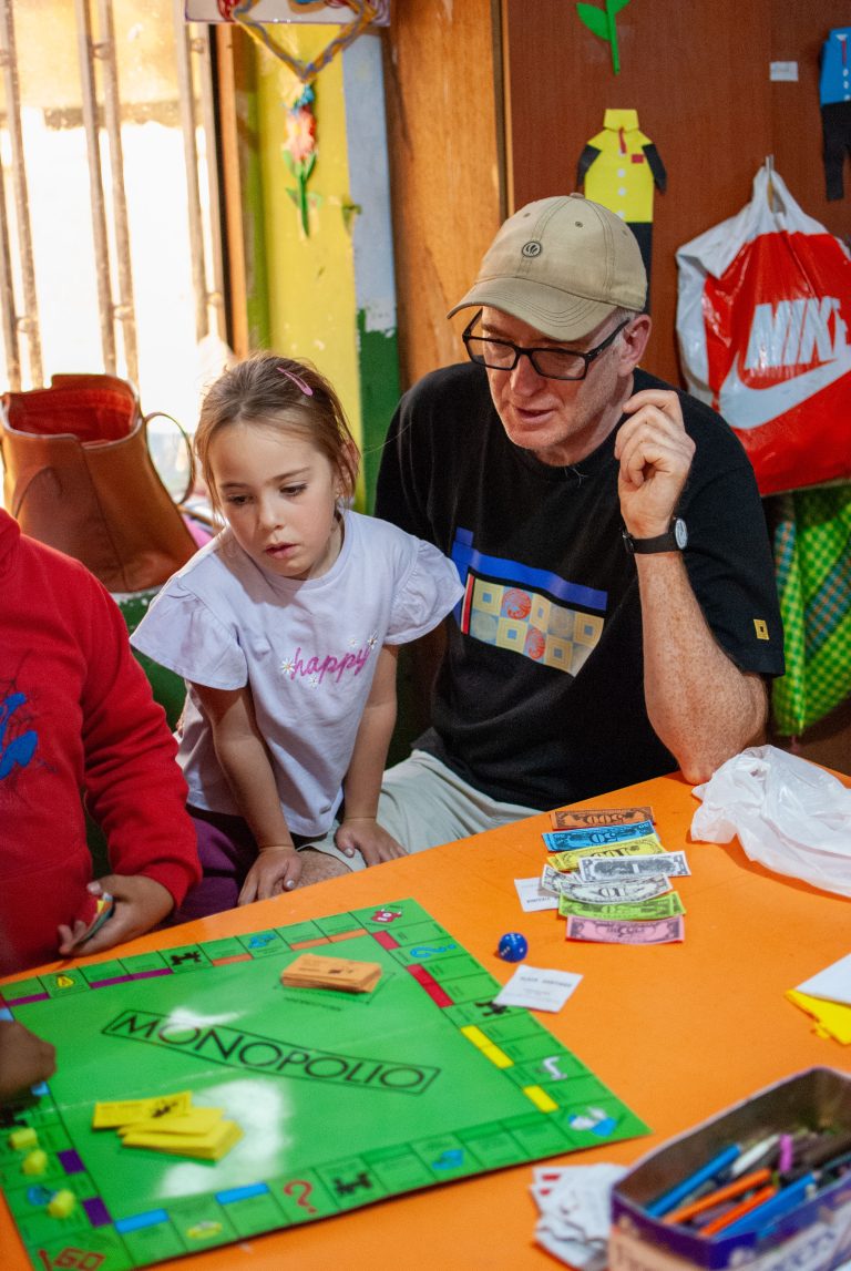 Volunteer helping children with an activity at Picaflor House