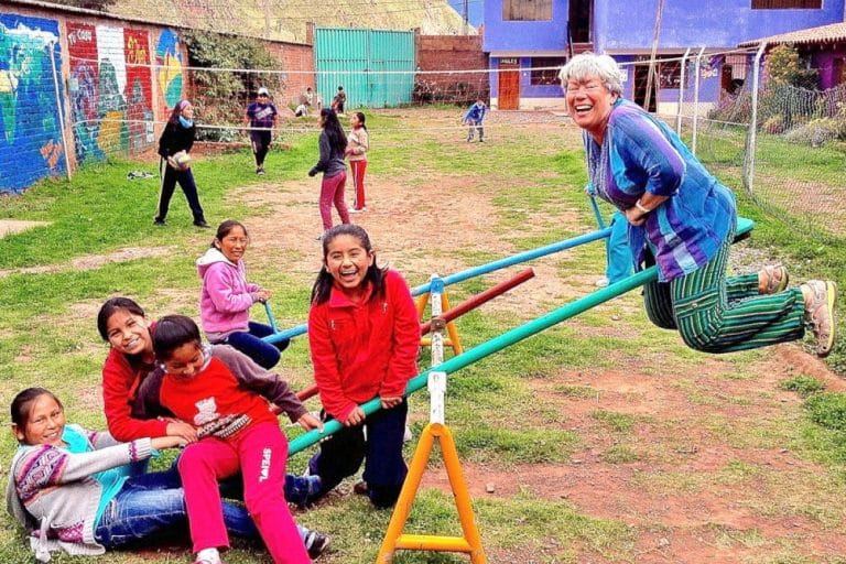 A volunteer and children on the seesaw at Picaflor House