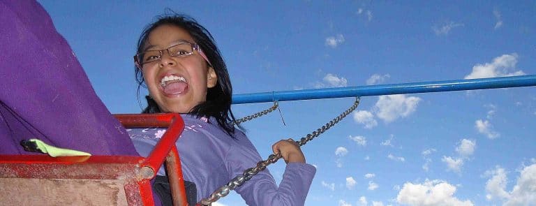 A girl laughing on the swings at Picaflor House