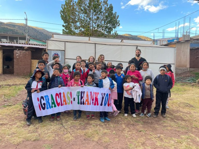 Volunteers and children holding a thank-you banner at Picaflor House in Cusco