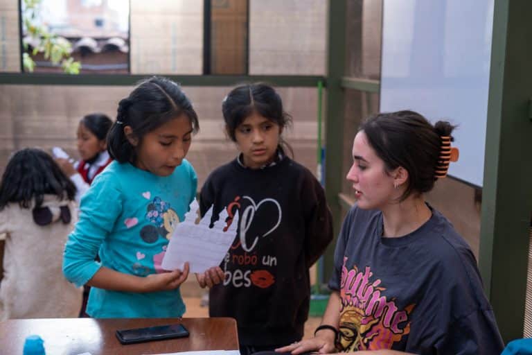 A volunteer helping two girls during a lesson in Cusco