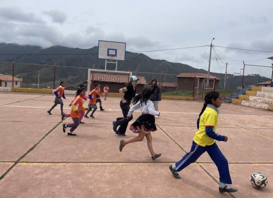 Larissa (central) playing football with students"