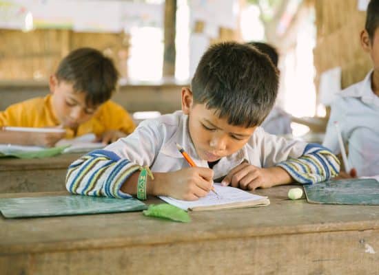 Child writing in exercise book at Helping Hands Cambodia"