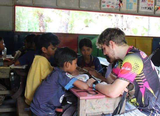 Volunteer supporting students reading"