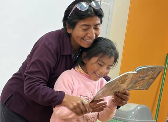 Mobile library teacher helping student read in Peru"
