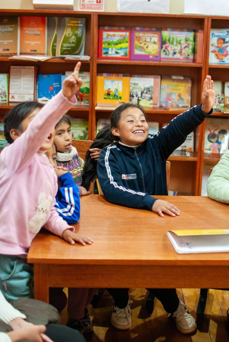 Children raising their hands in a library class in Cusco