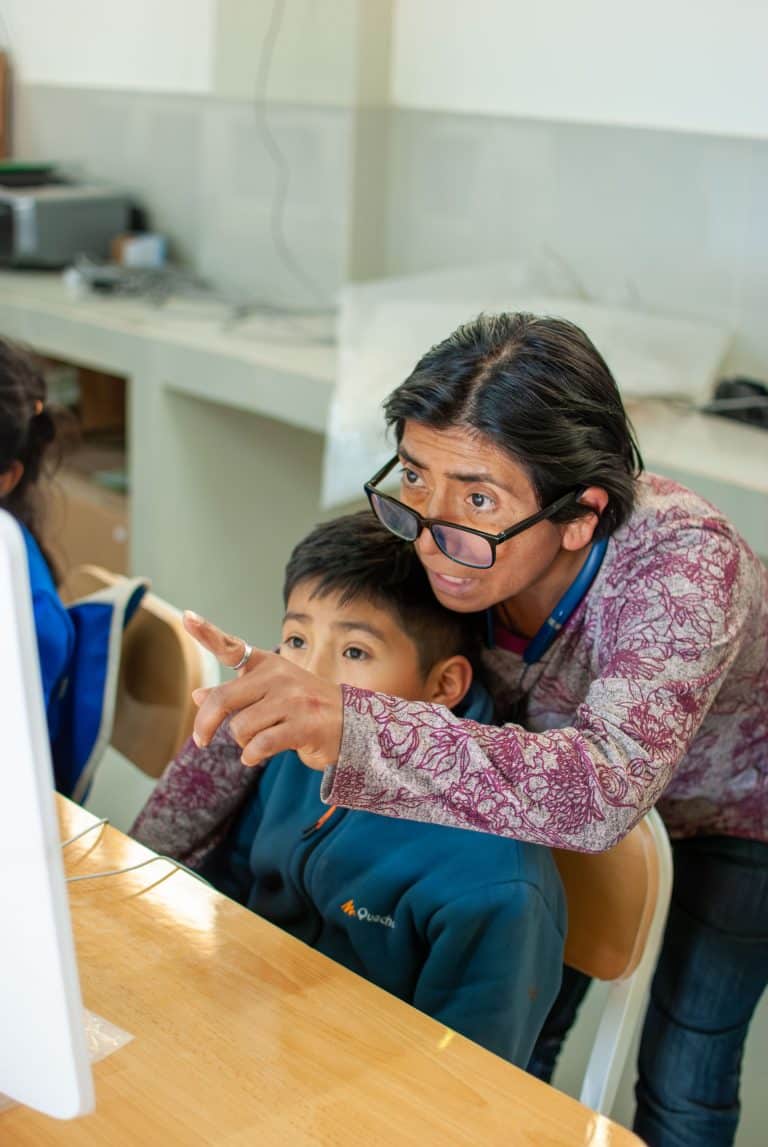 Teacher helping a young boy at the computer