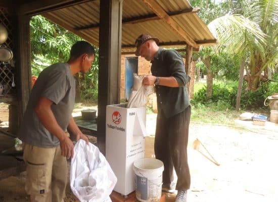 Volunteer helping fill a bio-sand water filter in Cambodia"