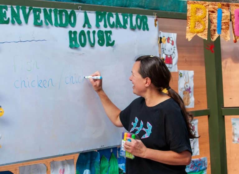 Volunteer teaching a lesson at the Picaflor House whiteboard